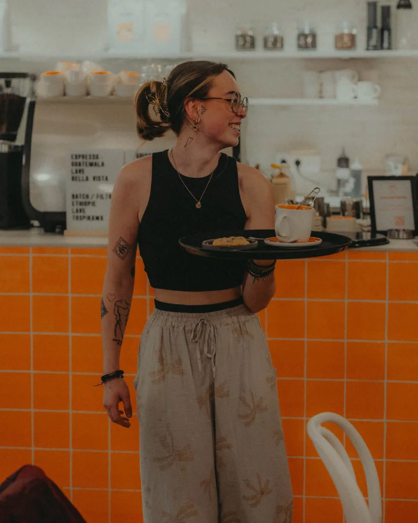 une serveuse de coffee shop à Toulouse qui tient un plateau avec un thé et un cookie