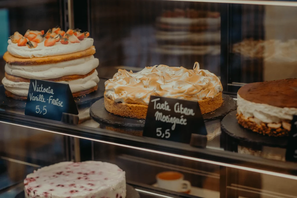 une vitrine de coffee shop à Toulouse avec des gâteaux dont un victoria sponge cake et une tarte citron meringuée